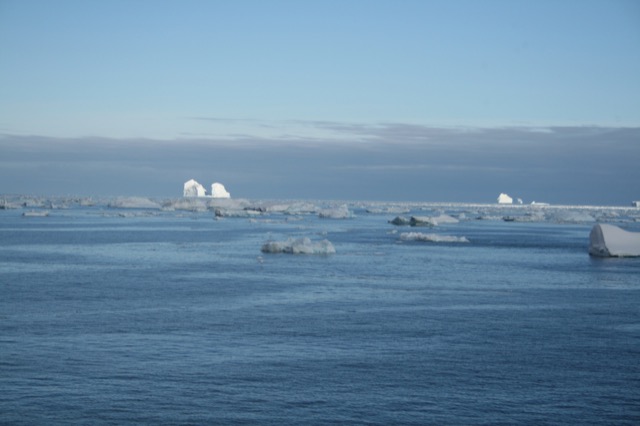 House-shaped icebergs off in the distance, catching the light